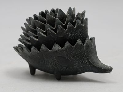 une sculpture noire représentant un hérisson sur une surface blanche