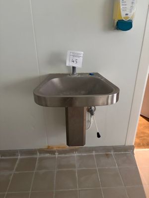 un lavabo dans un coin de la salle de bains, avec un distributeur de papier accroché au mur