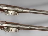 two silver and gold pistols are on display on a white surface