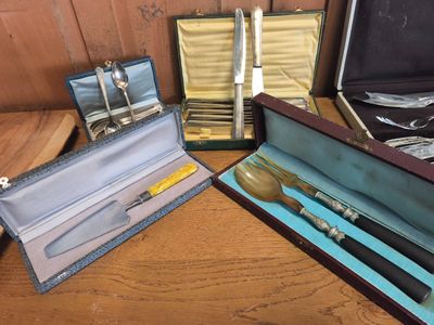 Plusieurs pièces d'argenterie sont posées dans un coffret sur une table en bois