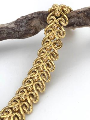a close up of a gold bracelet on a branch of a tree