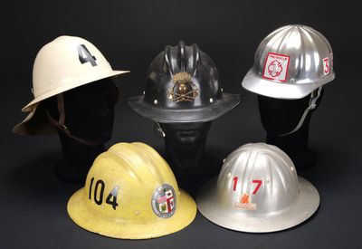 quatre casques de pompier sont alignés sur un fond noir