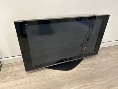 un téléviseur à écran plat noir posé sur un parquet