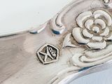 a close up of a silver spoon with a flower on it