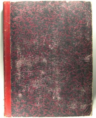 an old book sitting on top of a white table next to a red book