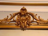 a mirror with a gold frame hanging on the wall