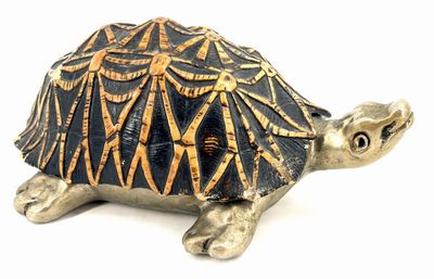 une petite figurine de tortue posée sur une surface blanche