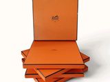 trois boîtes orange sont empilées les unes sur les autres sur une surface blanche