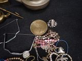 a lot of jewelry on a black table next to a teapot