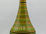a green and black vase with a light on top of it