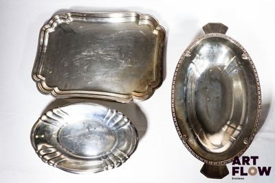 deux plateaux en argent et une cuillère en argent posés sur une surface blanche