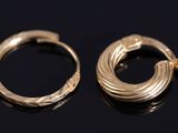 a pair of gold hoop earrings on a black surface