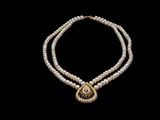 a necklace with pearls and a gold pendant on a black background