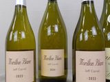 four bottles of white wine are lined up on a table