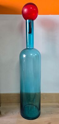 une bouteille en verre bleue surmontée d'une boule rouge
