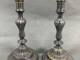 paire de bougeoirs anciens en argent sur un socle, sur fond gris