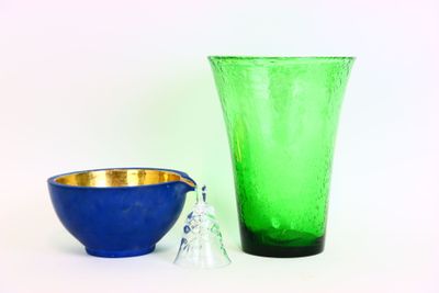 un vase en verre vert et un bol bleu placés l'un à côté de l'autre
