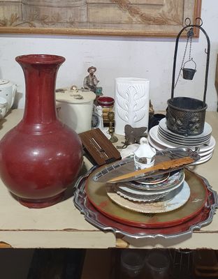 un vase rouge posé sur une table, à côté d'une pile d'assiettes