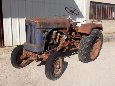 un tracteur rouillé garé devant un bâtiment