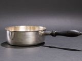 a silver saucepan with a wooden handle on a table