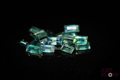 some pieces of green glass sitting on top of a black surface