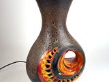un vase noir et orange surmonté d'une lampe
