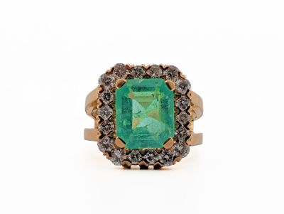 a close up of an emerald and diamond ring on a white background