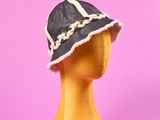 un chapeau noir et blanc posé sur une tête de mannequin, sur fond rose