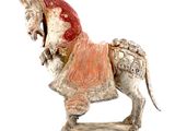 statue d'un cheval avec une selle sur le dos, sur fond blanc