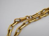 gros plan d'un bracelet en chaîne en or sur une surface blanche