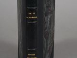 an old book with a black cover sitting on top of a table