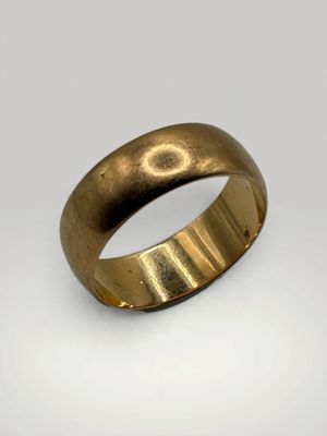 gros plan d'une bague en or sur une surface blanche