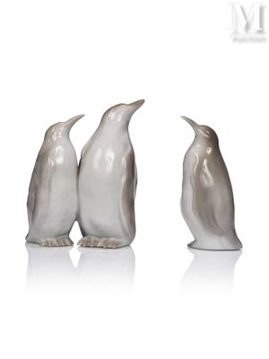 three penguins are standing next to each other on a white surface