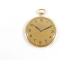 une montre de poche en or sur une surface blanche