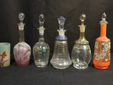 Plusieurs bouteilles en verre aux motifs variés sont alignées sur un fond noir.