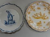 two plates with blue and yellow designs on them sitting on a table