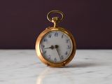 une montre de poche en or posée sur une table en marbre