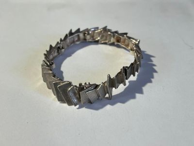 bracelet en argent orné de pointes sur un fond blanc