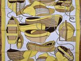 une écharpe jaune et marron ornée de bateaux, posée sur un parquet