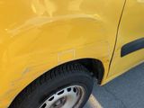 a close up of a yellow car that has a denting on it