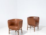 deux fauteuils en cuir marron posés sur un sol blanc
