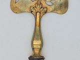 a gold bell on the wall next to a black and white vase