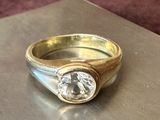 une bague en or sertie d'un diamant, posée sur une table