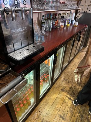 une personne debout devant un comptoir sur lequel sont posées des boissons