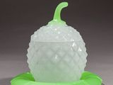 a glass pine cone with a green leaf on it