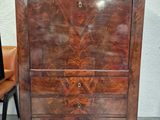 une commode en bois avec des tiroirs et une chaise à côté