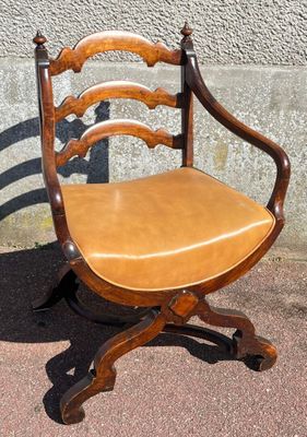 a wooden chair with a leather seat sitting on a sidewalk