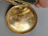 a person holding a gold pocket watch in their hand