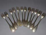 six forks are arranged in a circle on a gray surface