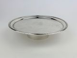a close up of a silver plate on a white surface